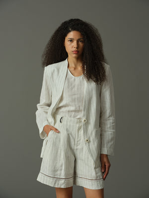 Woman wearing a light gray suit with shorts against a plain background