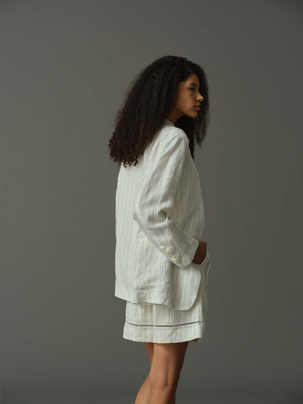 Woman wearing a light-colored outfit against a gray background