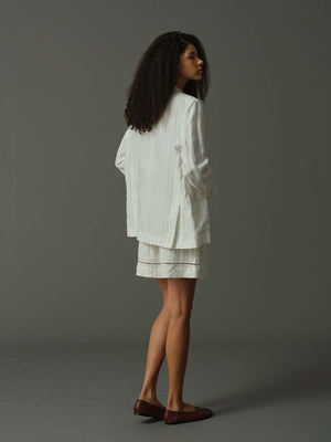 Woman wearing a white outfit against a gray background