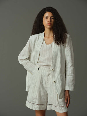 Woman wearing a light-colored suit with a plain background