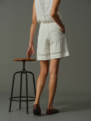 Person wearing a white outfit standing next to a stool on a gray background