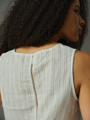 Woman wearing a light-colored sleeveless top with a subtle pattern.