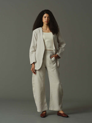 Woman wearing a beige suit standing against a gray background