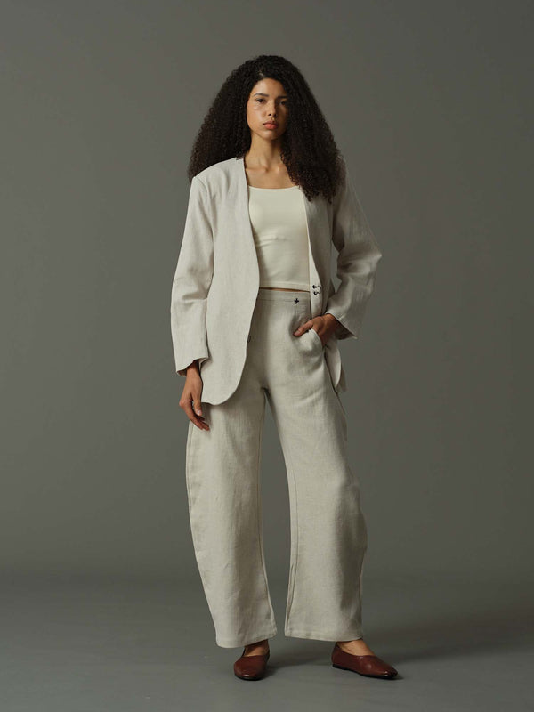 Woman wearing a beige suit standing against a gray background