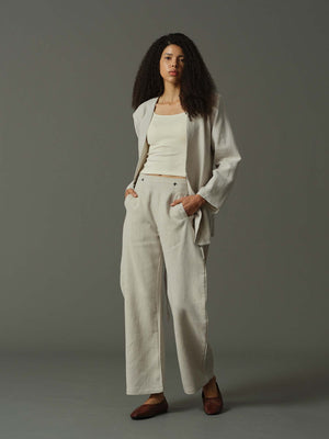 Woman wearing a light gray suit with a white top on a gray background