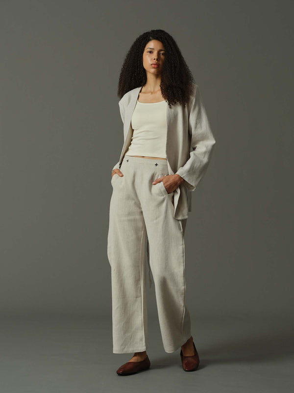 Woman wearing a light gray suit with a white top on a gray background