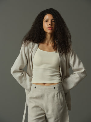 Woman wearing a beige outfit against a gray background