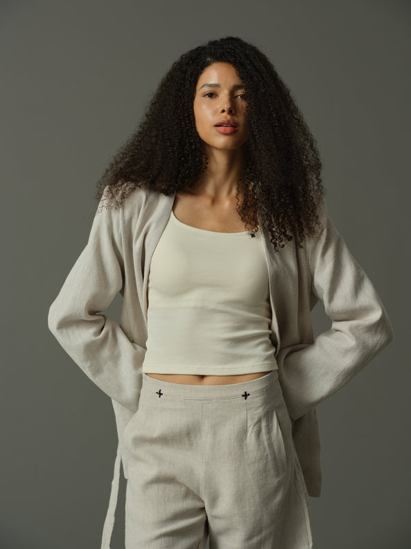 Woman wearing a beige outfit against a gray background