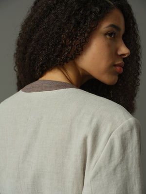 Woman wearing a light gray cardigan over a brown shirt against a neutral background