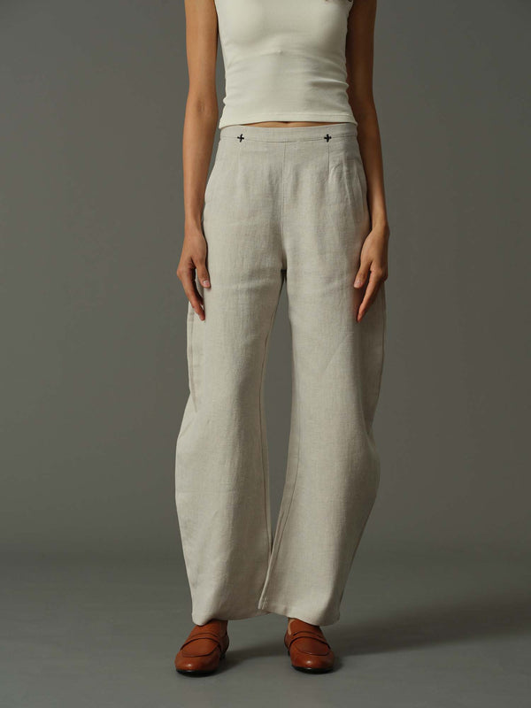 Person wearing light-colored wide-leg pants and a white top on a gray background