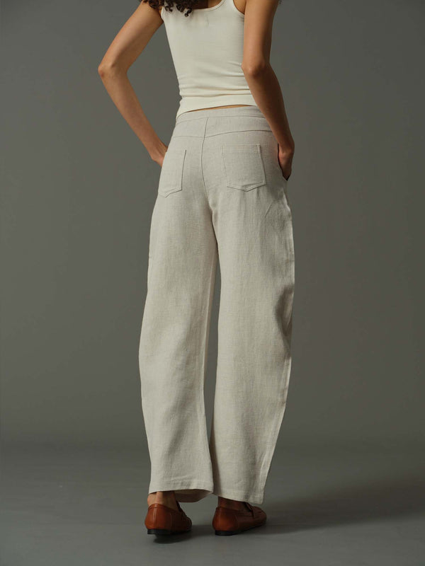 Person wearing beige wide-leg pants and a white top on a gray background