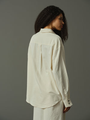 Woman wearing a light-colored shirt against a gray background