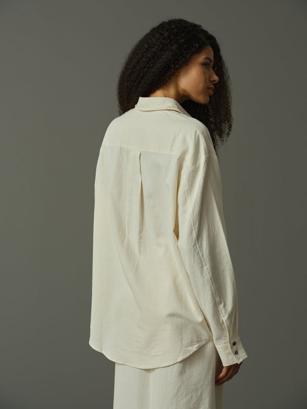 Woman wearing a light-colored shirt against a gray background