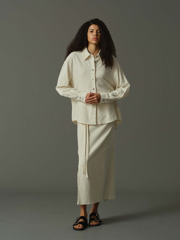 Woman wearing a beige outfit against a gray background