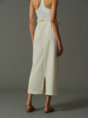 Person wearing a white tank top and wide-leg pants on a gray background