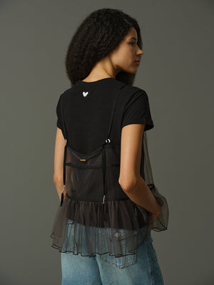 model wearing a black layered outfit with sheer cami and black t shirt underneath against a gray background