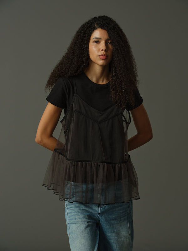model wearing a black layered outfit with sheer cami and black t shirt underneath against a gray background