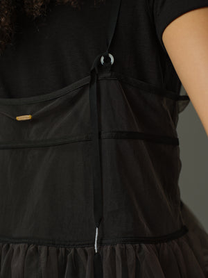 close up of a black layered outfit with sheer cami and black t shirt underneath against a gray background