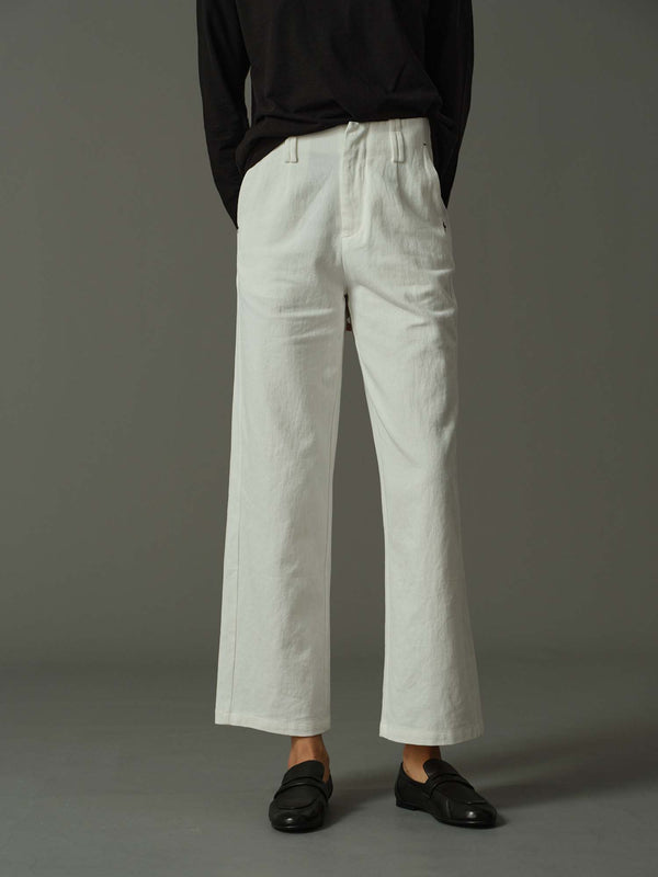 Person wearing white pants and black shoes on a gray background