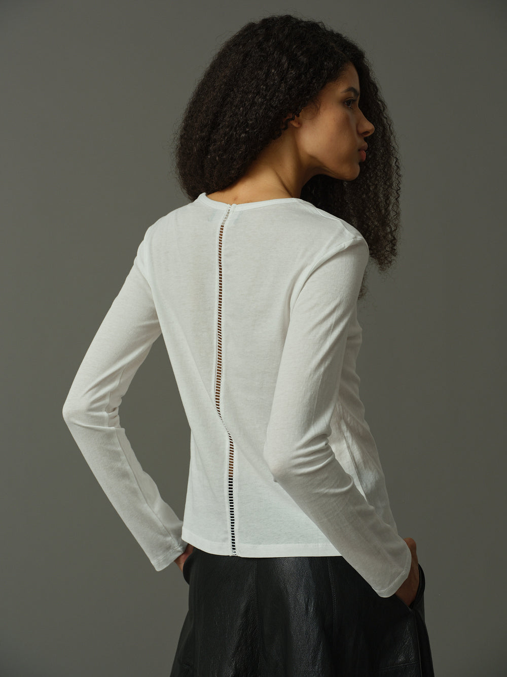Woman wearing a white long-sleeve top with a zipper detail on a gray background