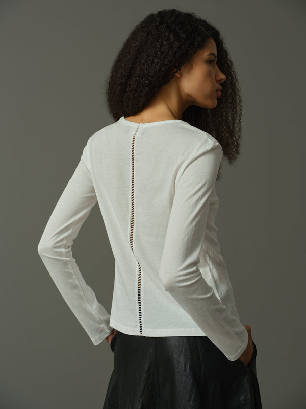 Woman wearing a white long-sleeve top with a zipper detail on a gray background
