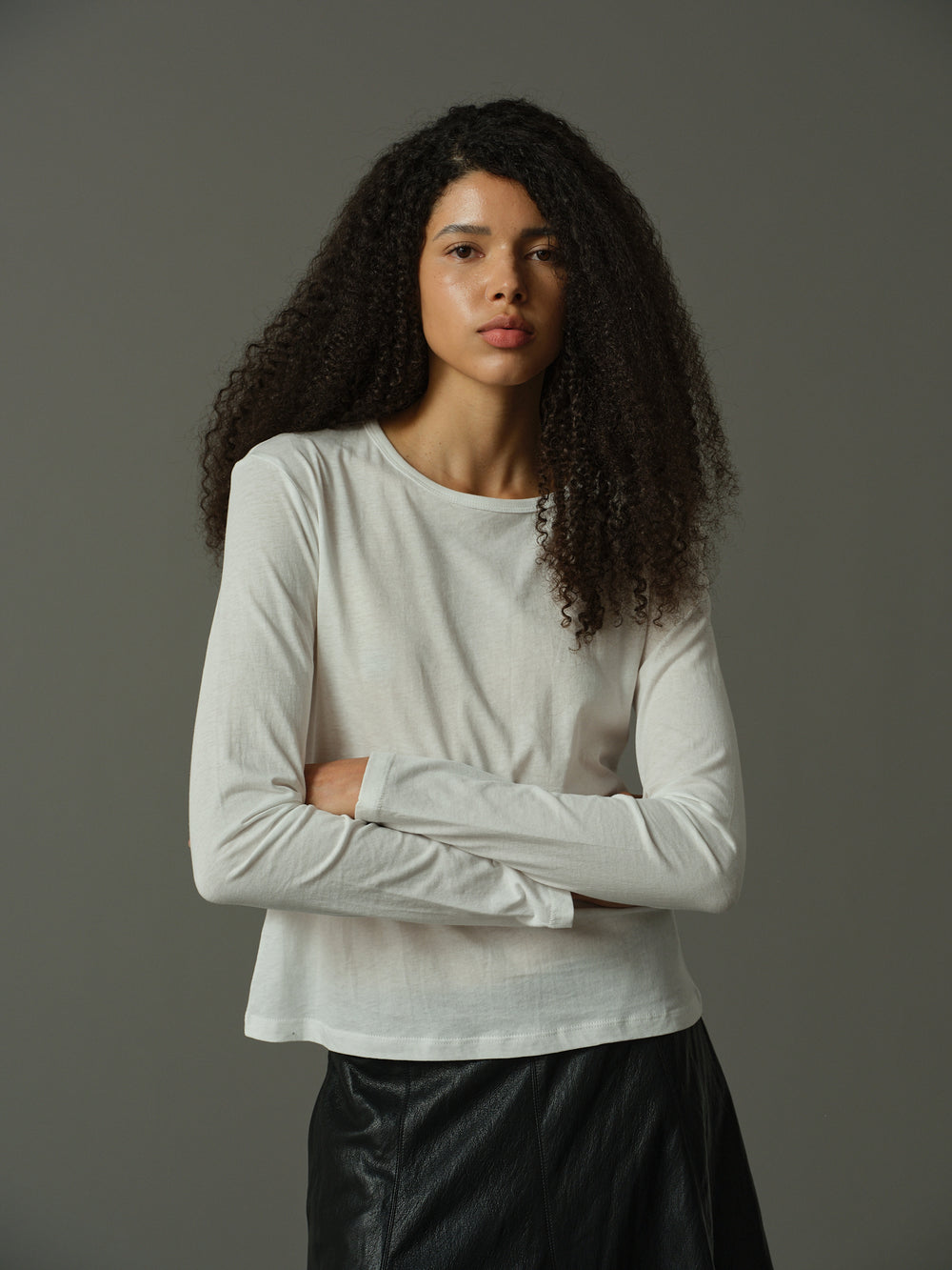 Woman wearing a white long-sleeve top with a zipper detail on a gray background