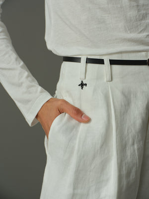 Person wearing a white shirt and light-colored pants with a black belt against a gray background
