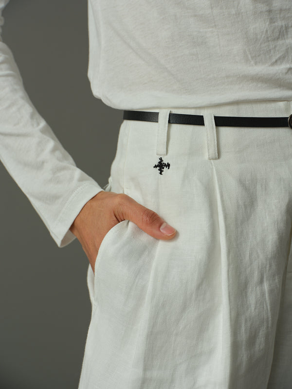 Person wearing a white shirt and light-colored pants with a black belt against a gray background