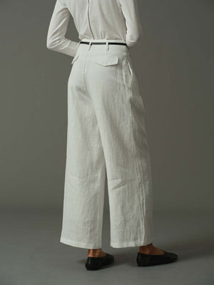 Person wearing a white shirt and wide-leg pants on a gray background