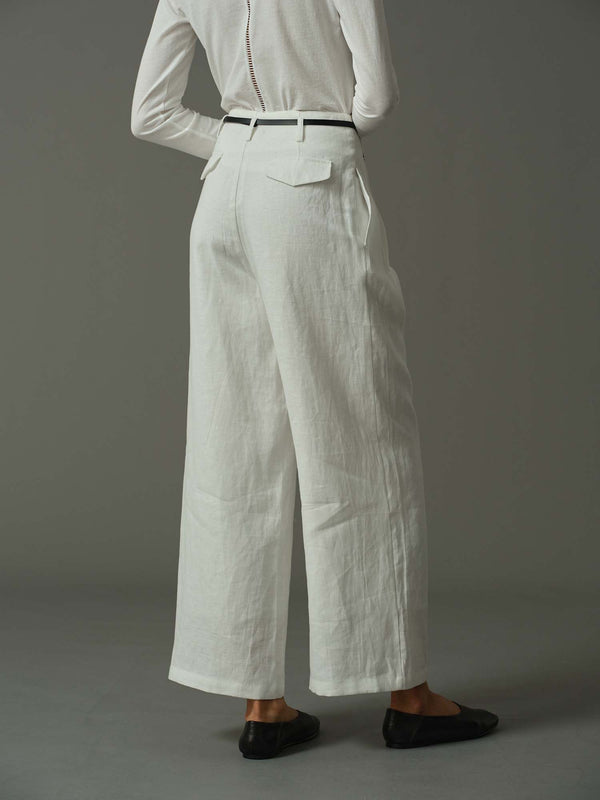 Person wearing a white shirt and wide-leg pants on a gray background