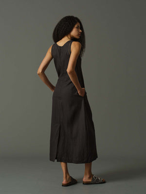Woman wearing a black sleeveless dress against a gray background
