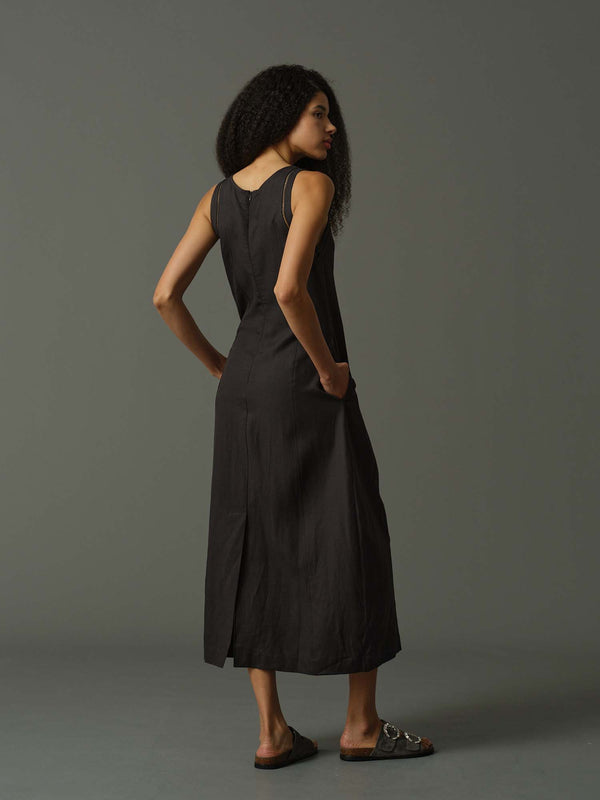 Woman wearing a black sleeveless dress against a gray background