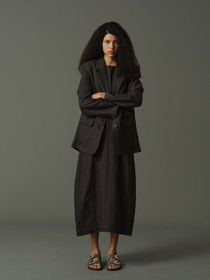 Woman wearing a dark gray suit against a plain background