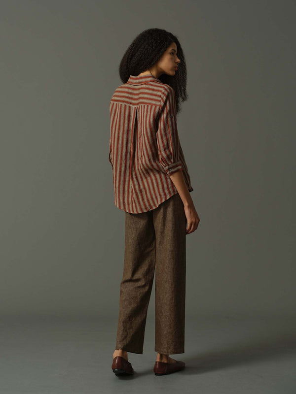 Person wearing a striped shirt and brown pants against a gray background