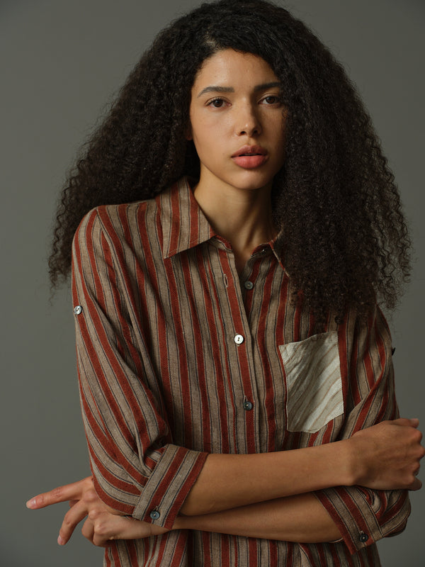 Woman wearing a striped shirt with contrast pocket against a gray background