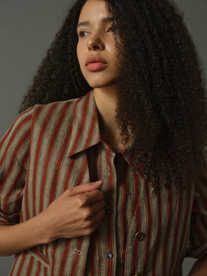 Woman wearing a striped shirt and matching striped vest against a neutral background