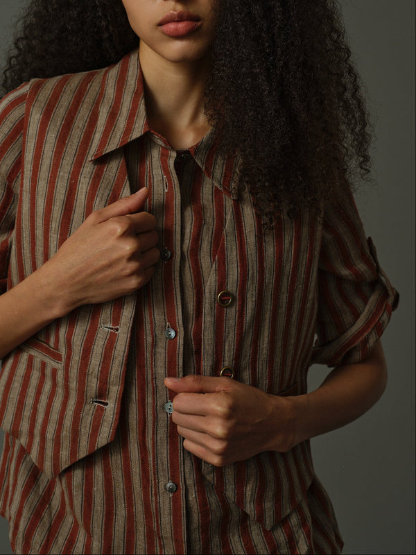 Woman wearing a striped shirt and matching striped vest against a dark background