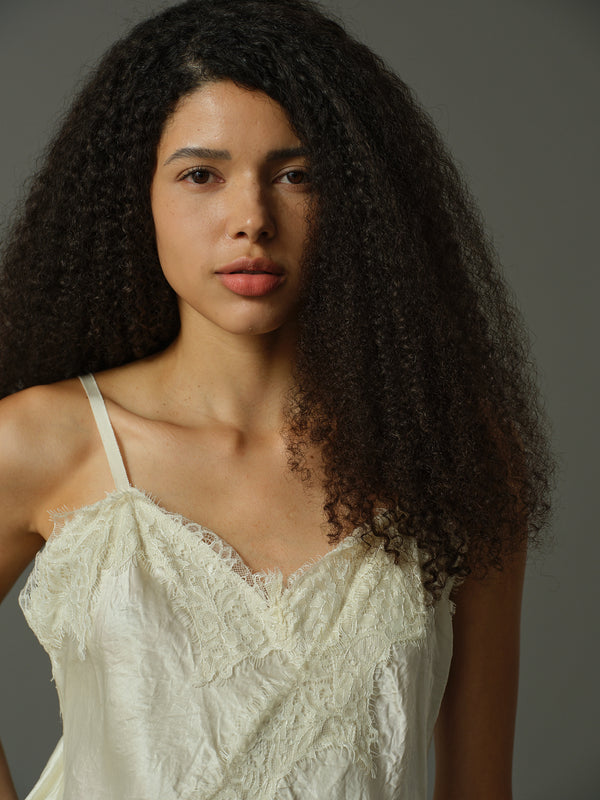 Woman wearing a white lace top against a gray background