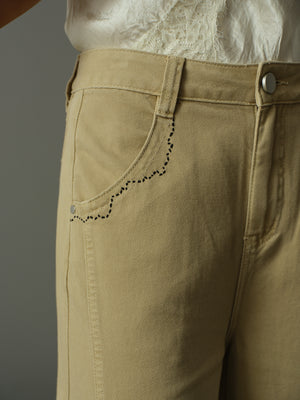 Close-up of beige pants with a plain background