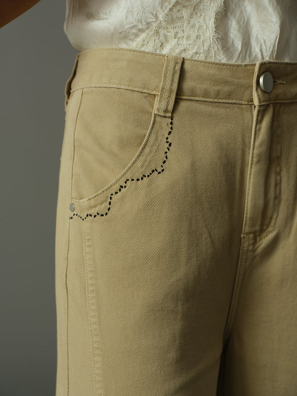 Close-up of beige pants with a plain background