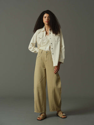 Woman wearing a white shirt and beige pants against a gray background