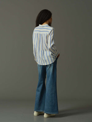 Person wearing a striped shirt and blue jeans against a gray background