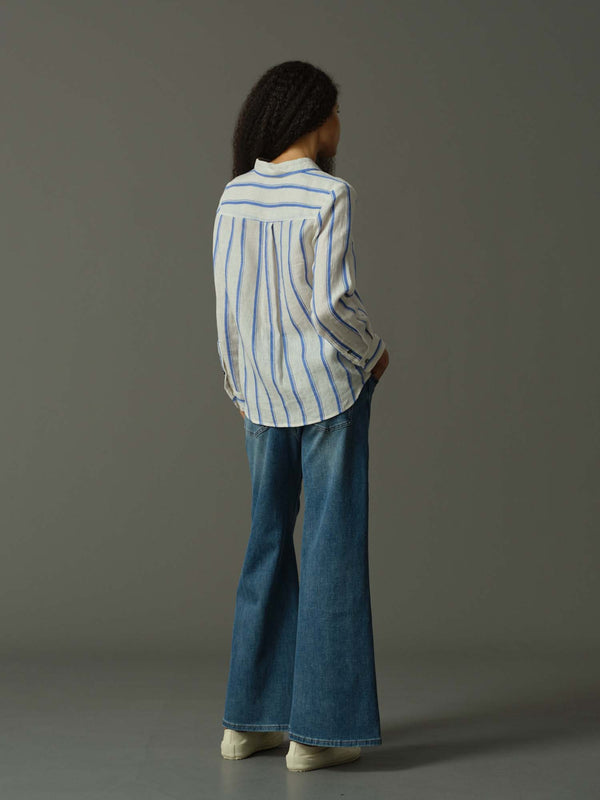 Person wearing a striped shirt and blue jeans against a gray background