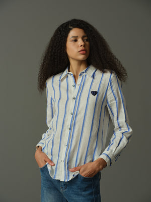 Woman wearing a striped shirt with a dark logo on a gray background