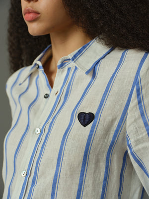 Close-up of a person wearing a striped shirt with a heart design on a plain background