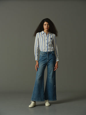 Person wearing a striped shirt and blue jeans on a gray background