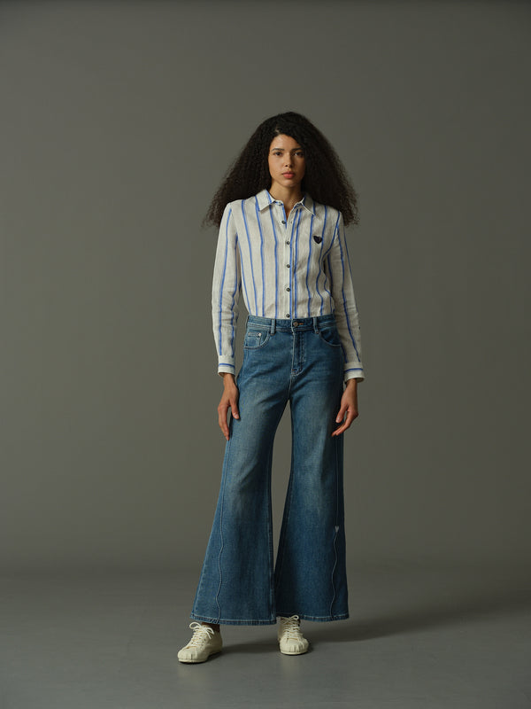 Person wearing a striped shirt and blue jeans on a gray background
