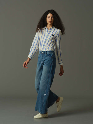 Woman wearing a striped shirt and blue jeans on a gray background
