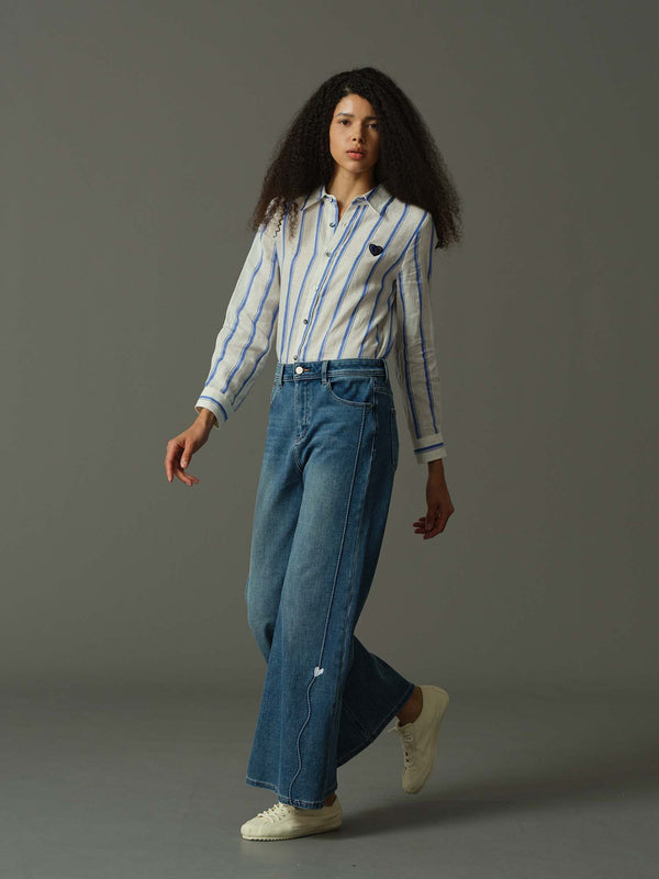 Woman wearing a striped shirt and blue jeans on a gray background