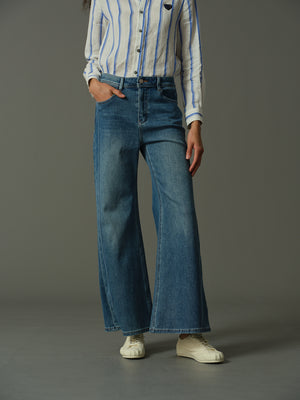 Person wearing blue jeans and a striped shirt on a gray background